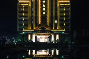 Un hotel con una entrada destacada y su reflejo en el agua.