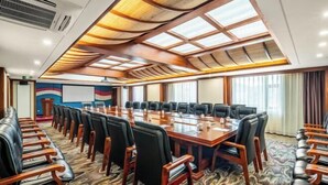 Una sala de conferencias con una larga mesa, sillas y una pantalla de proyector.