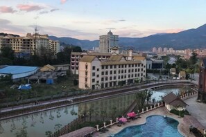 Un hotel con piscina, rodeado de montañas y otros edificios.