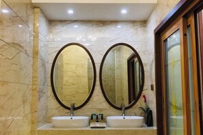 A bathroom with two sinks, each with a mirror above. The walls are tiled with a marble pattern. - Menluo Wa Jing Luxury Grand Hotel(Hulu Town Wa Tribe Branch) (Cangyuan)