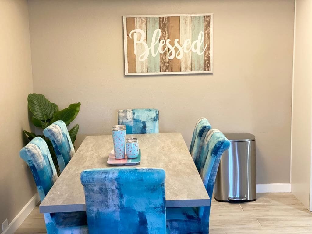 A dining area with a table and chairs, a wall-mounted sign, and a trash can.