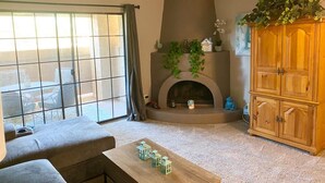 Una sala de estar con chimenea, ventilador de techo y un gran aparador de madera.