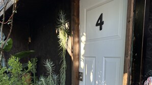 Eine weiße Tür mit der Nummer 4, ein weißes Gitter und eine Fußmatte davor.