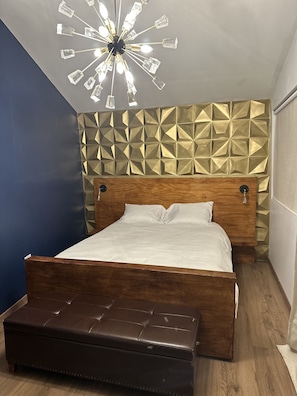 Restful retreat with a central bed, geometric-patterned wall, and ceiling light fixture.