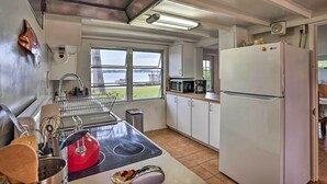 A compact kitchen with a sink, microwave, and refrigerator, large windows offering a view of the outdoors. - Waterfront Vacation Rental on Lake Mirror! (Winter Haven)