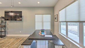 A room with a dark wooden table, white base, and a TV mounted on the wall.
