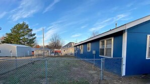 A fenced outdoor area with a blue building, a trailer, and a grassy field. - The Little Fish in Eufaula (Eufaula)