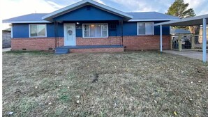 A single-story house with a blue and red exterior, a front door, and a small porch. - The Little Fish in Eufaula (Eufaula)