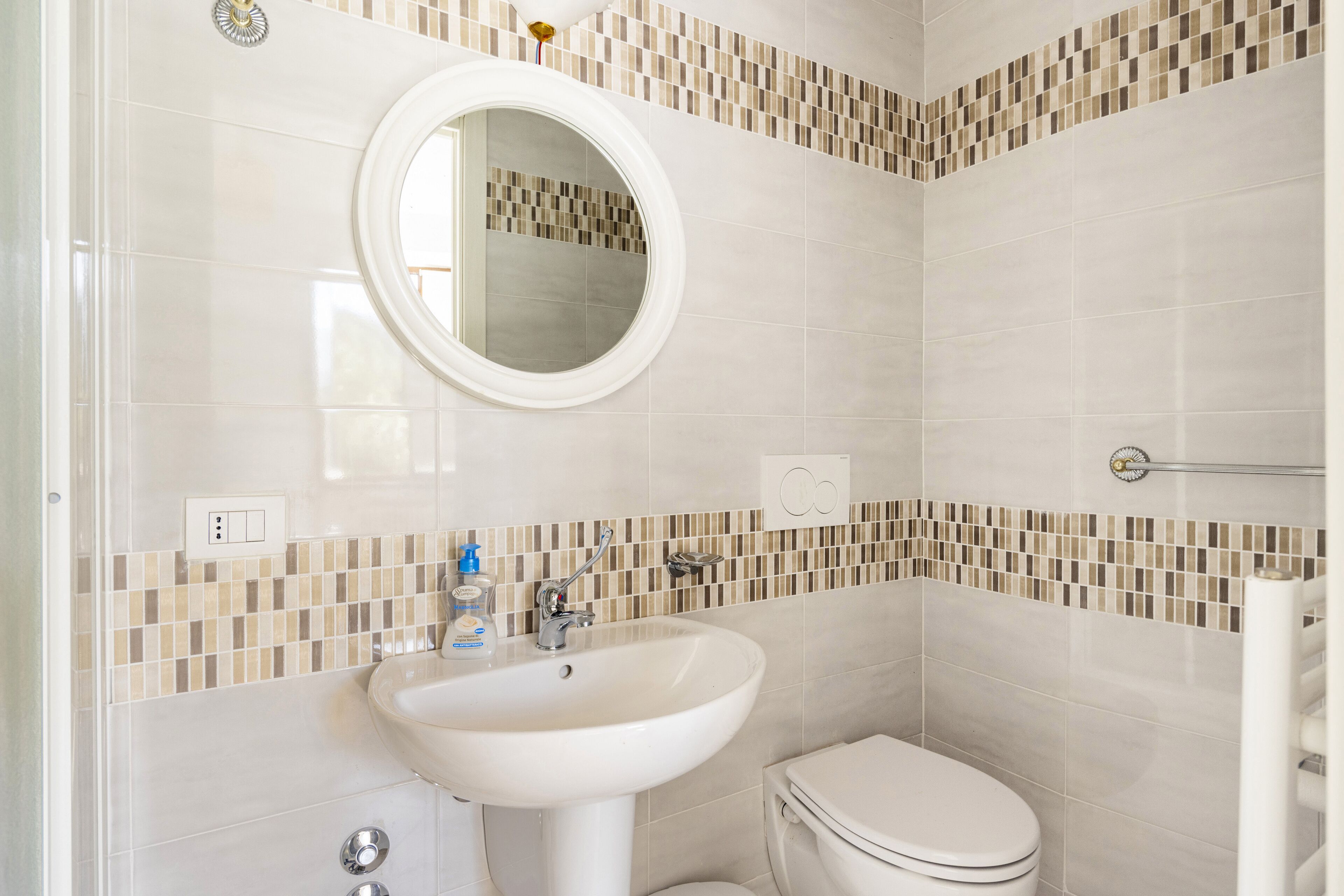 Un baño con lavamanos, espejo e inodoro blancos.