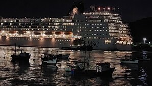 Un gran crucero amarrado en un puerto, con varias embarcaciones más pequeñas cerca.
