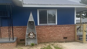 Un bâtiment à la façade bleue, avec une partie inférieure en briques et un toit en métal.