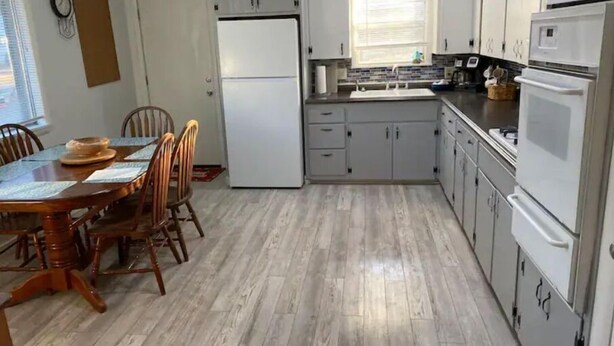 Une cuisine compacte avec un coin repas, comprenant un réfrigérateur, des placards et un four à micro-ondes.
