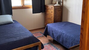 A bedroom with two beds, a dresser, a fan, and a window with curtains. - Welcome to our Wichita Home - Easy Close Access to Turnpike South Side (Wichita)