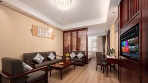 A living room with a sofa set, a coffee table, a TV, and a decorative screen. - Fall In Love With Nujiang Grand Canyon Hotel (Lushui)