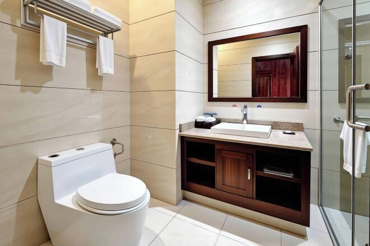 Uma casa de banho moderna com sanita, lavatório e espelho.
