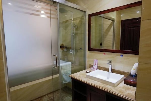 Une salle de bain avec une douche à parois de verre, un lavabo avec un miroir au-dessus et un meuble en bois en dessous.