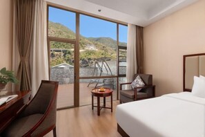 A hotel room with a large window, a bed, a desk, and a chair. - Fall In Love With Nujiang Grand Canyon Hotel (Lushui)