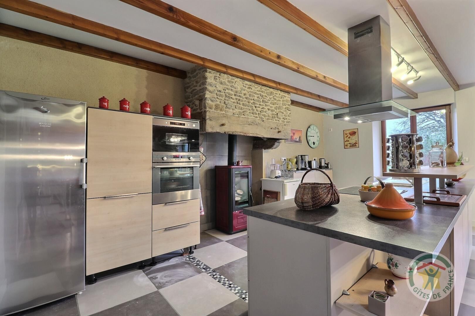 A modern kitchen with stainless steel appliances, a stone wall, and a checkered floor.