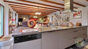 A modern kitchen with a built-in dishwasher, stainless steel appliances, and a wooden ceiling. - La Petite Prairie - Baguer Morvan (BAGUER MORVAN)