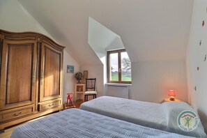 A bedroom with two beds, a wooden wardrobe, a window with a view, and a lamp on the nightstand. - La Petite Prairie - Baguer Morvan (BAGUER MORVAN)