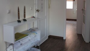 Een hotelkamer met een witte console tafel, een deur met een raam en een houten vloer.