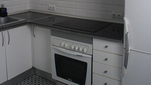 Een keuken met witte kastjes, een zwart-wit geruite vloer, een roestvrijstalen afzuigkap en een witte koelkast.