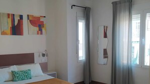 Een hotelkamer met een bed, een nachtkastje, een spiegel en twee abstracte schilderijen aan de muur.