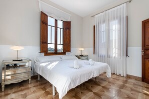 A bedroom with a large bed, two bedside tables, a dresser, and a window with wooden shutters. - YourHouse Can Bombarda, large house with private pool (Llubi)