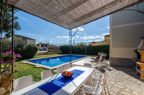 A covered outdoor area with a pool, dining table, chairs, and a grill. - YourHouse Can Bombarda, large house with private pool (Llubi)