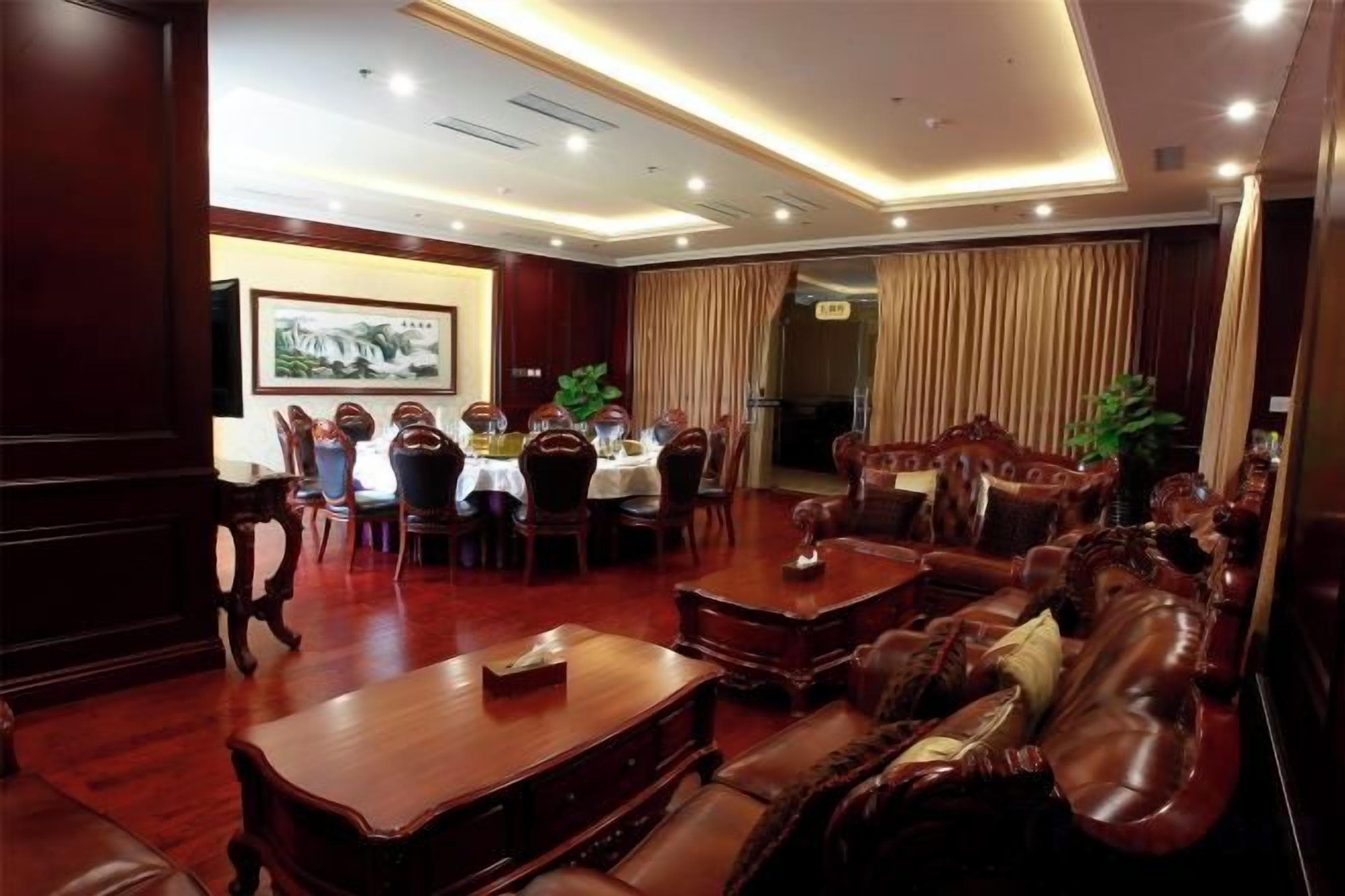 A hotel lobby with a dining area, leather sofas, and a reception desk.