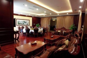 Un hall d’hôtel comprenant un espace repas, des canapés en cuir et un comptoir d’accueil.