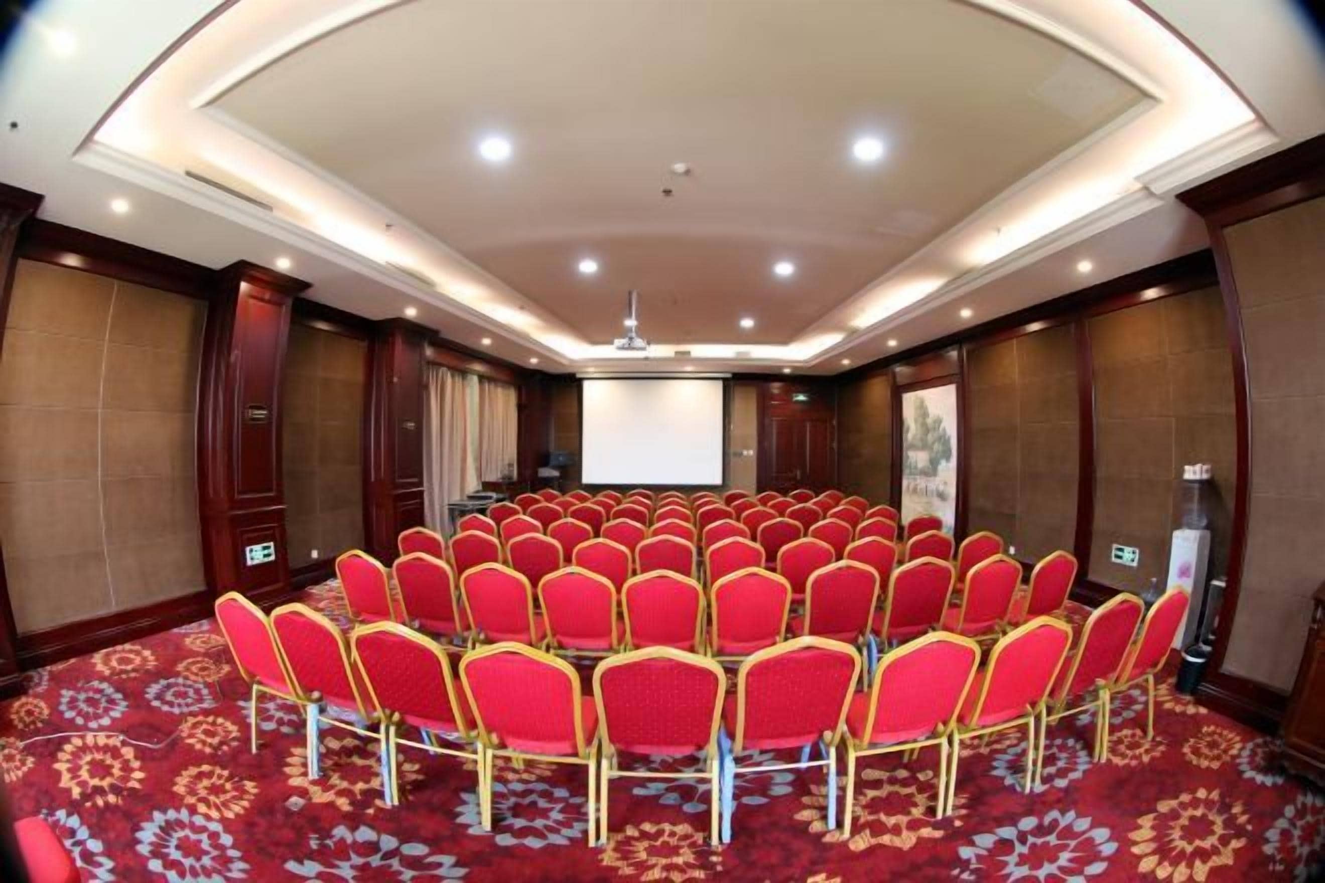 A conference room with a circular seating arrangement, a projector screen, and a carpeted floor.