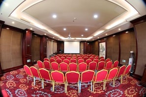 A conference room with a circular seating arrangement, a projector screen, and a carpeted floor. - Aohua International Hot Spring Hotel (Linyi)