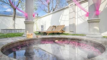 A spa area with a hot spring, wooden loungers, and a stone fountain.