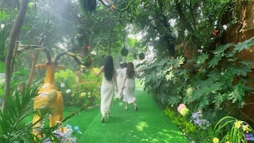 Un sendero serpentea por un jardín exuberante, lleno de follaje y flores.