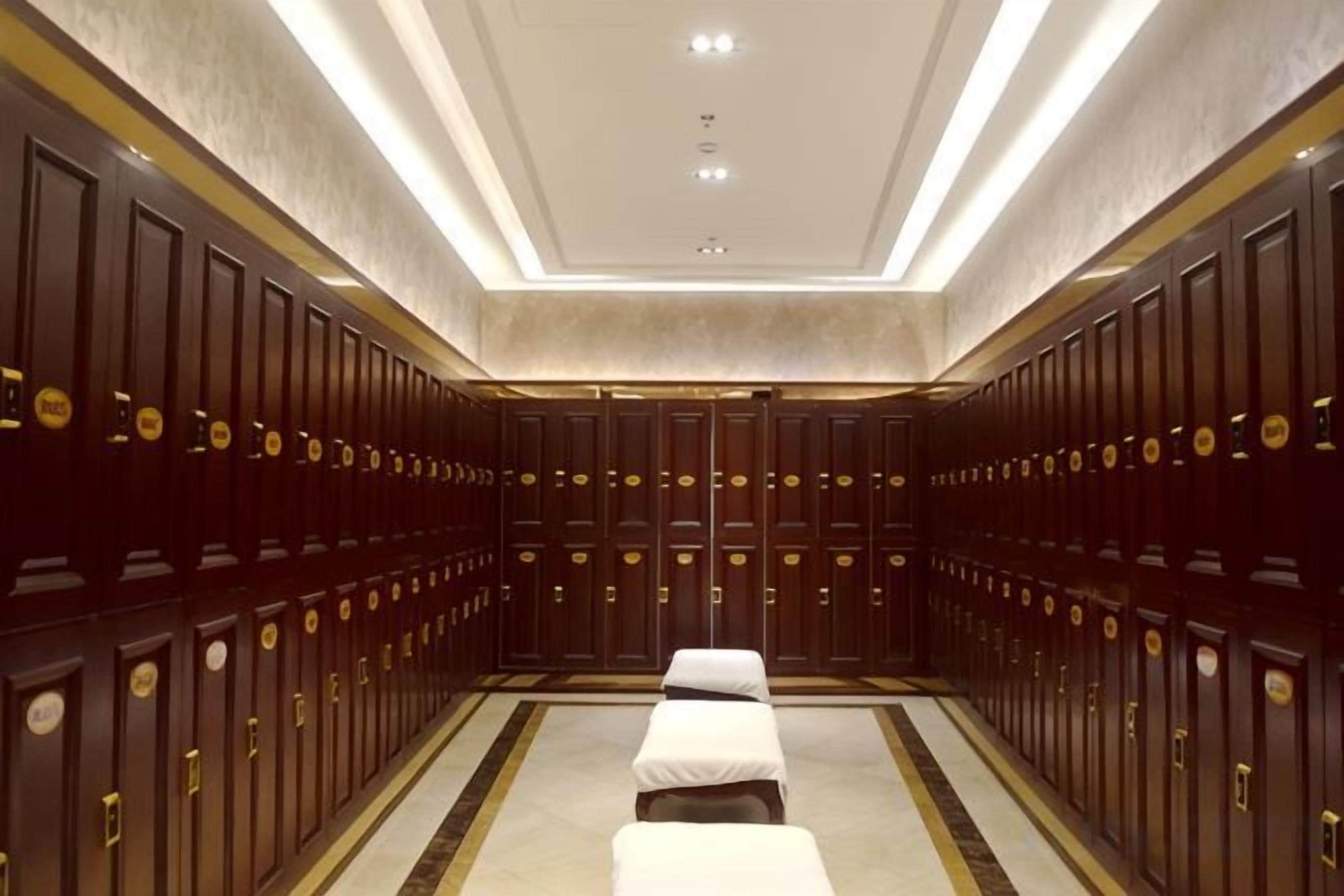 A hotel room with a large mirror, a bed, a bedside table, and a wardrobe.