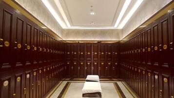 A hotel room with a large mirror, a bed, a bedside table, and a wardrobe.
