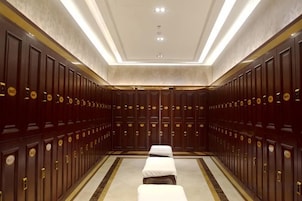 Una habitación de hotel con un espejo grande, una cama, una mesita de noche y un armario.