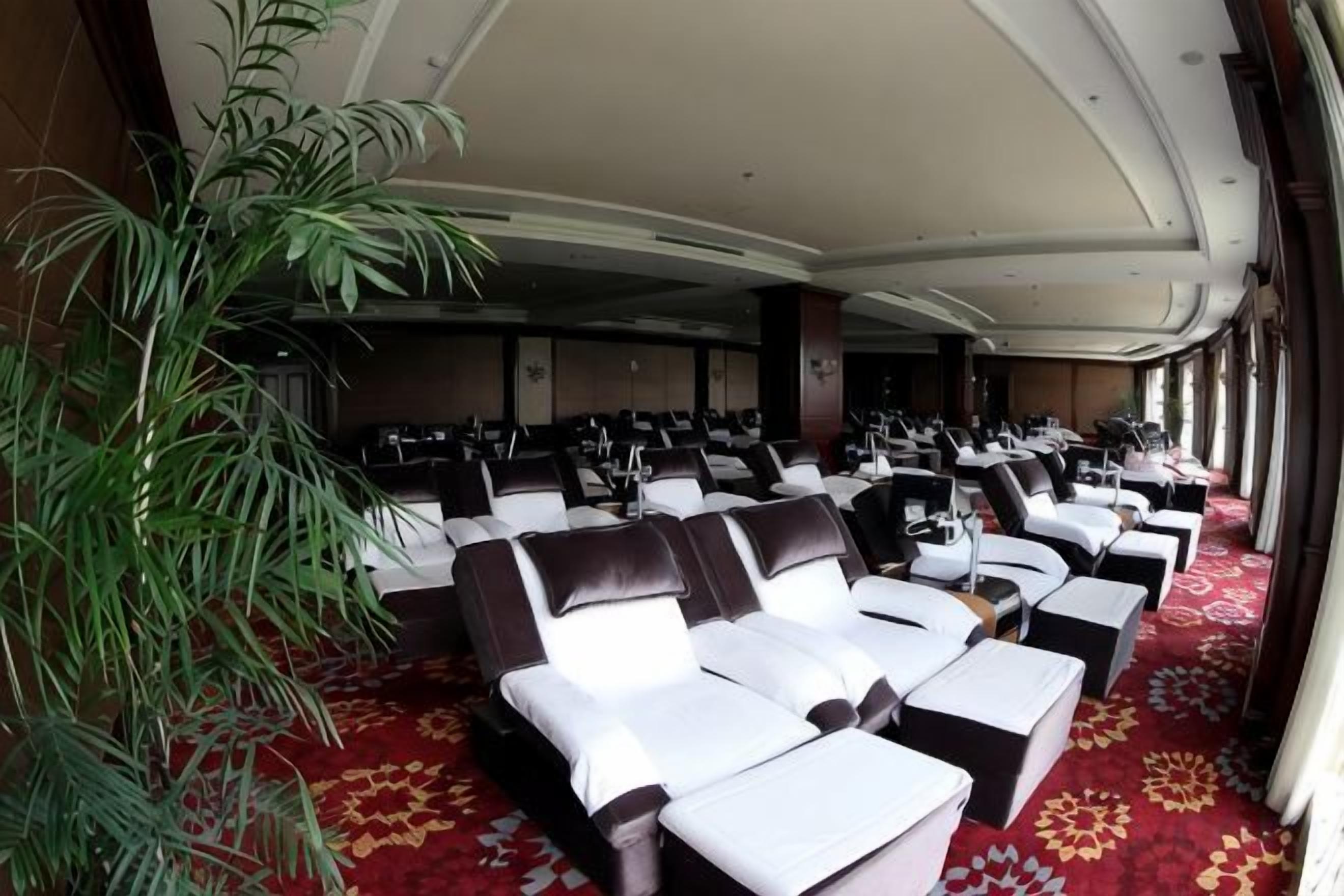 A hotel room with a large bed, a sitting area with chairs, and a large window.