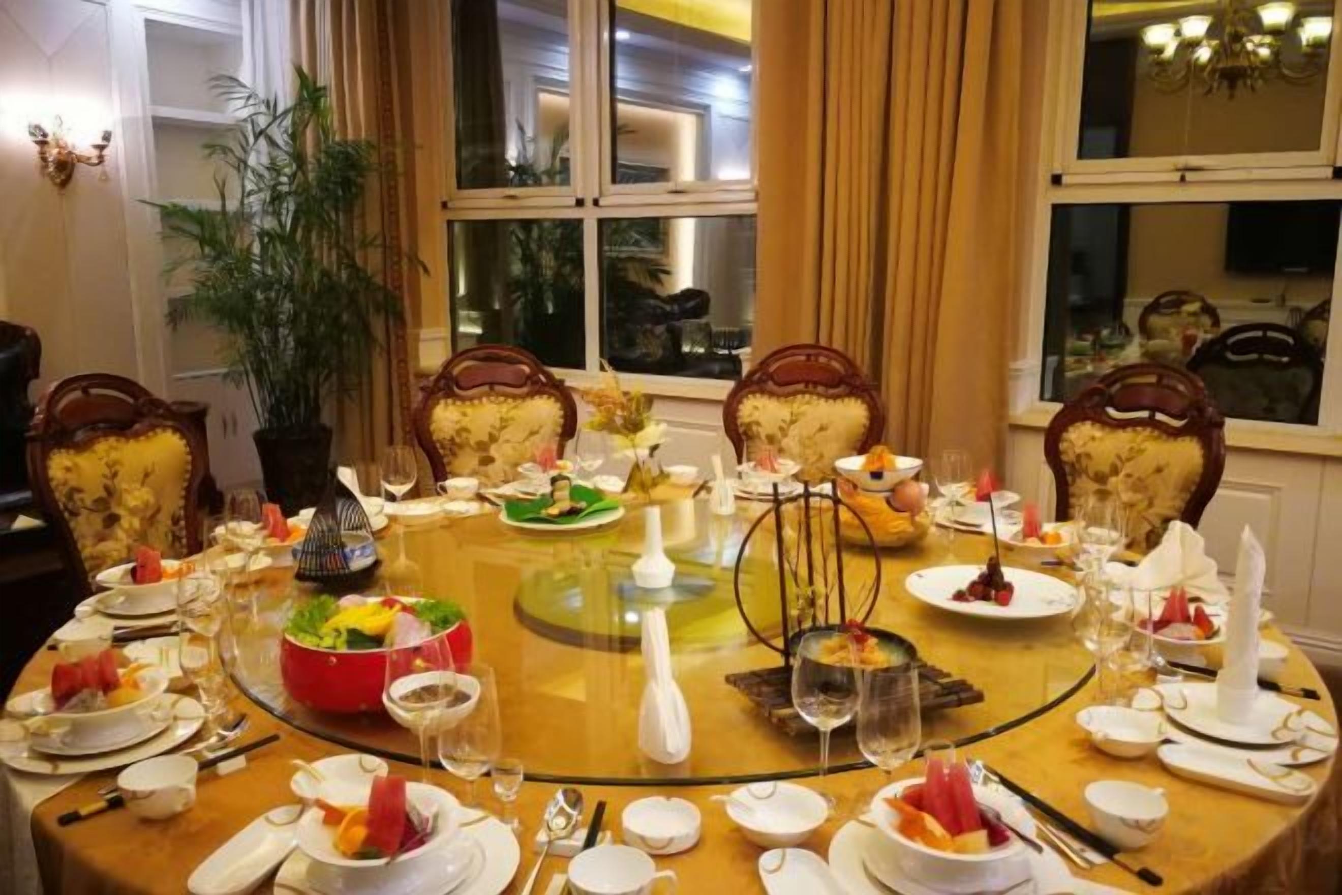 A round dining table set for a meal with chairs, plates, glasses, and cutlery.