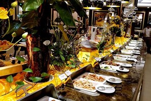 Un buffet proposant une variété de plats et agrémenté d’un arbre décoratif en guise de centre de table.