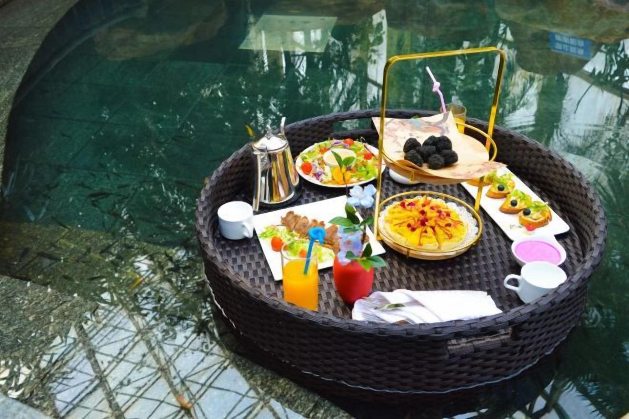 A wicker tray with breakfast items by a pool.