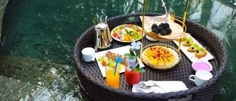 A wicker tray with breakfast items by a pool.