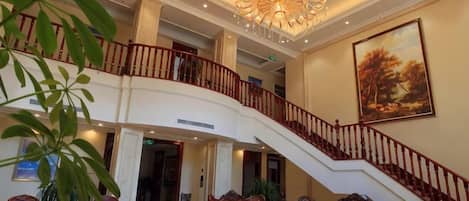 A grand lobby with a staircase, seating area, and a chandelier.