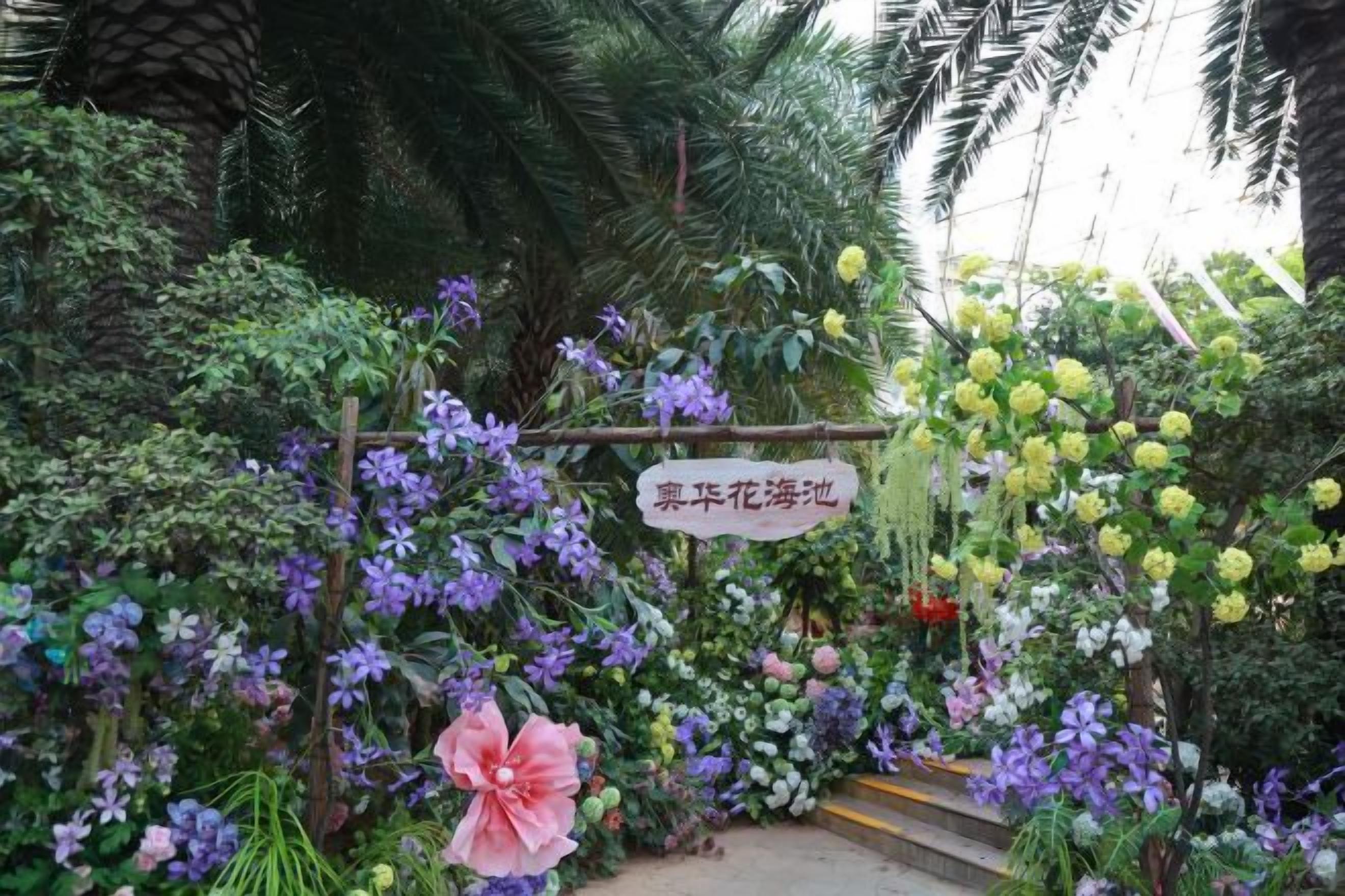 A garden with a variety of flowers and a sign.
