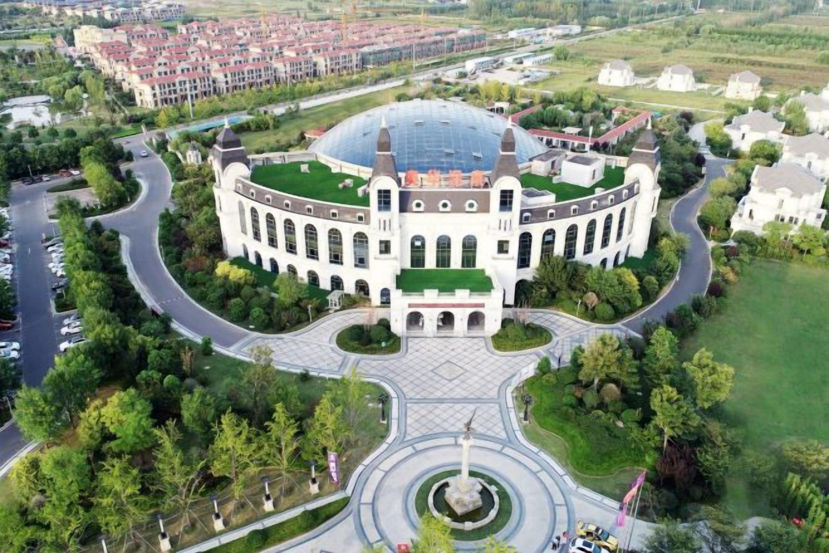 A large, circular building with a central dome and a surrounding garden.