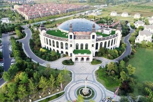 Egy nagy, kör alakú épület, központi kupolával és azt körülvevő kerttel.