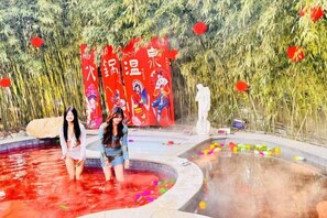 A hot spring area with a pool and a statue in the background. - Aohua International Hot Spring Hotel (Linyi)