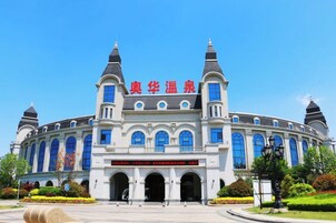 Um edifício imponente com estilo arquitetônico clássico, apresentando uma entrada central com portas em arco e uma grande placa acima.