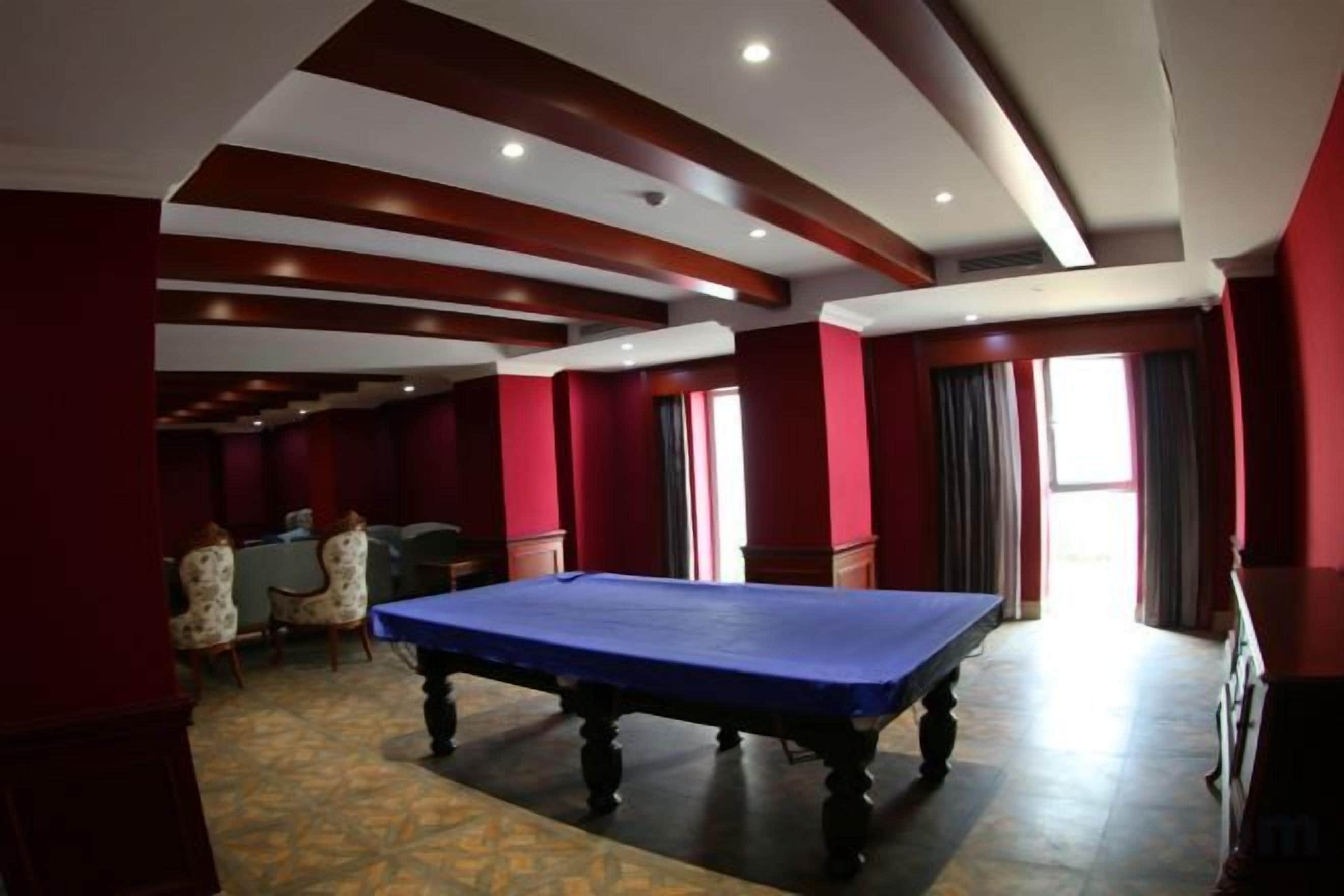 A pool table in a room with red walls and a patterned carpet.